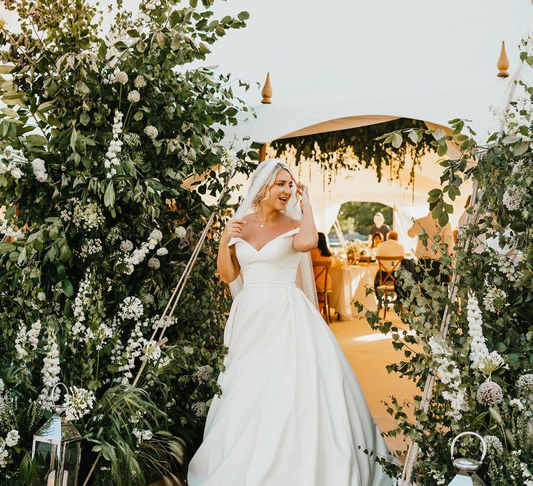 Bride wears off-the-shoulder princess wedding dress with drop veil in her blonde hair 