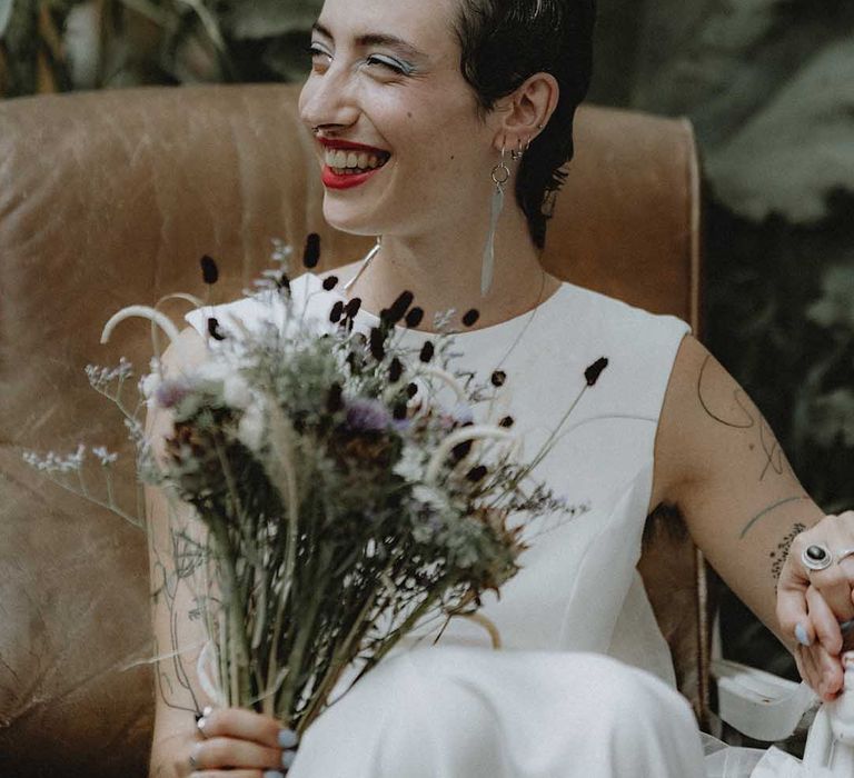 Lisa wears red lipstick and dark hair slicked back into 20s styling complete with DIY bridal bouquet 