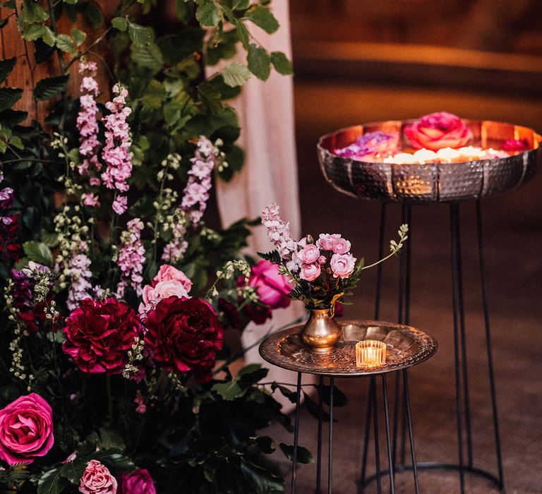 Metallic gold plates on black metal legs hold tea light and flower arrangements decorating the wedding venue to fit the wedding theme 