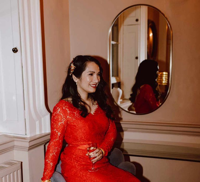 Bride wearing red lace wedding dress with long sleeves, red and gold hair accessories and golden closed toe wedding heels