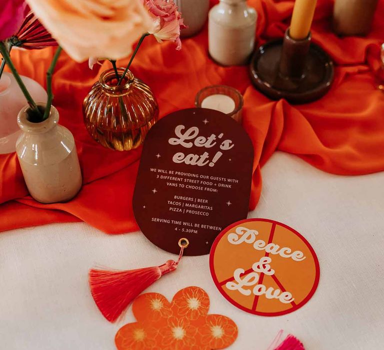 Retro wedding stationery at Northern Monk Refectory Leeds - orange and mauve retro wedding stationery with white bold lettering and tassels with disco ball decorations 