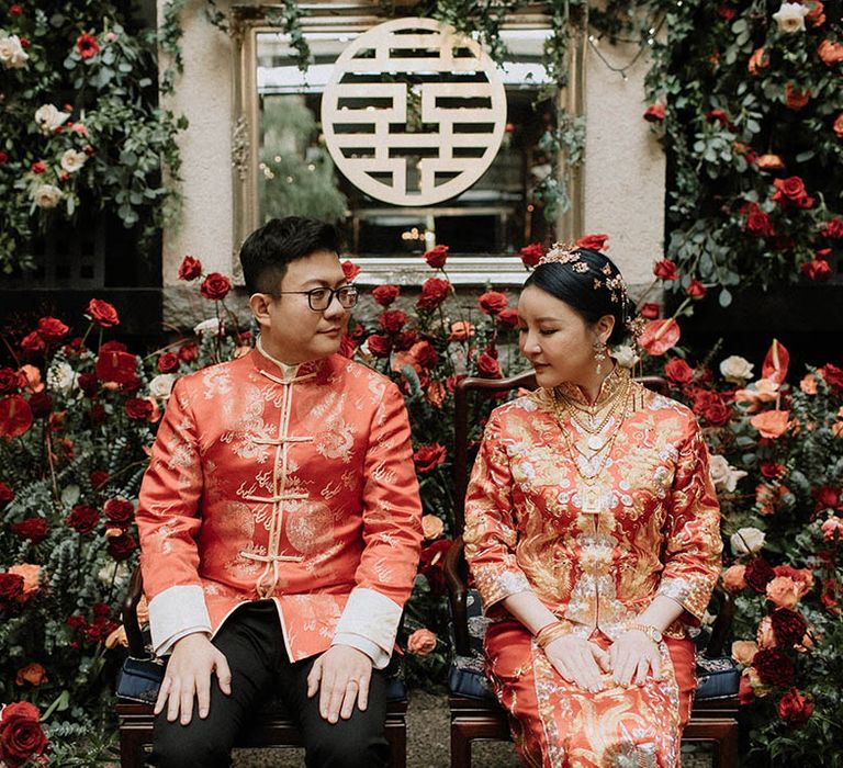 Bride and groom in red and gold traditional Chinese wedding attire for their Chinese tea ceremony 