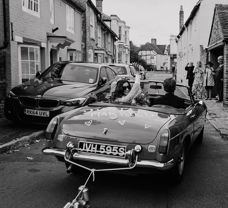 Vintage blue wedding car with tin cans tied to the bumper of the car and 'just married' painted on the trunk of the car 