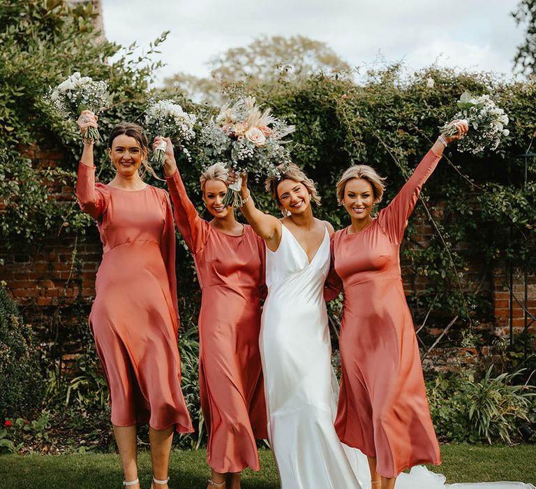 Bridal party in midi bridesmaid dresses with long sleeves in satin fabric