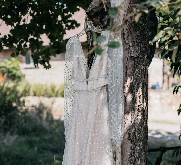 Sheer long sleeve sparkly wedding dress hanging in a tree at Viking themed wedding 