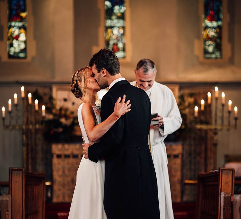 The bride and groom share their first kiss as a married couple at their wedding ceremony 