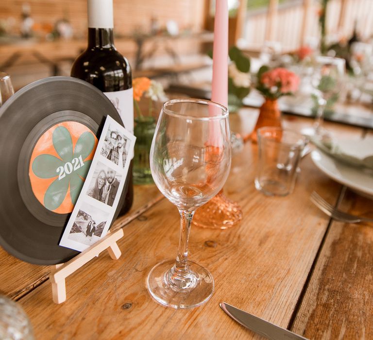 Vinyl record welding table number sign decorated with polaroid photos of the bride and groom 