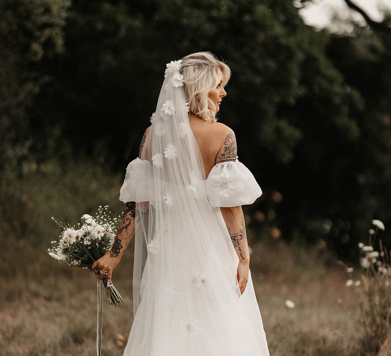 Bride in 3D applique veil and dress with white bouquet of wildflowers 