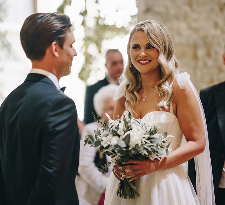 The bride and groom smile and stare at each other at their classic luxe black tie wedding at Stone Barn