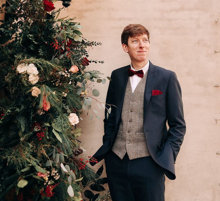 Winter wedding in December with groom wearing a navy suit and red bow tie 