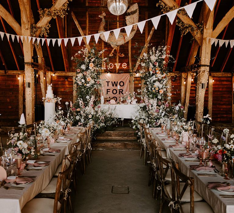 Neutral wedding flower columns decorating the top table with neutral wedding flowers, a neon sign and banner 