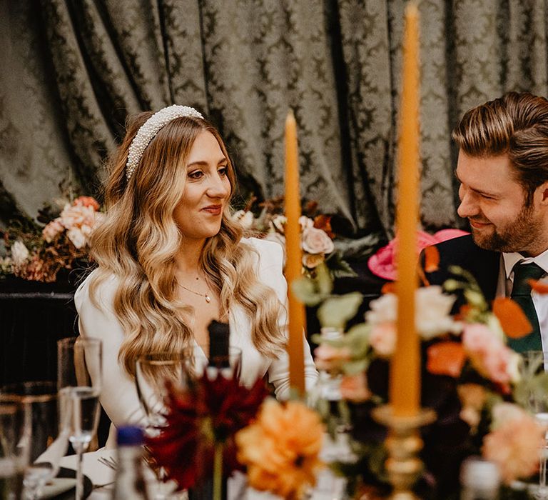 Orange taper candles decorate the wedding tablescape with bride and groom seated at the top table 