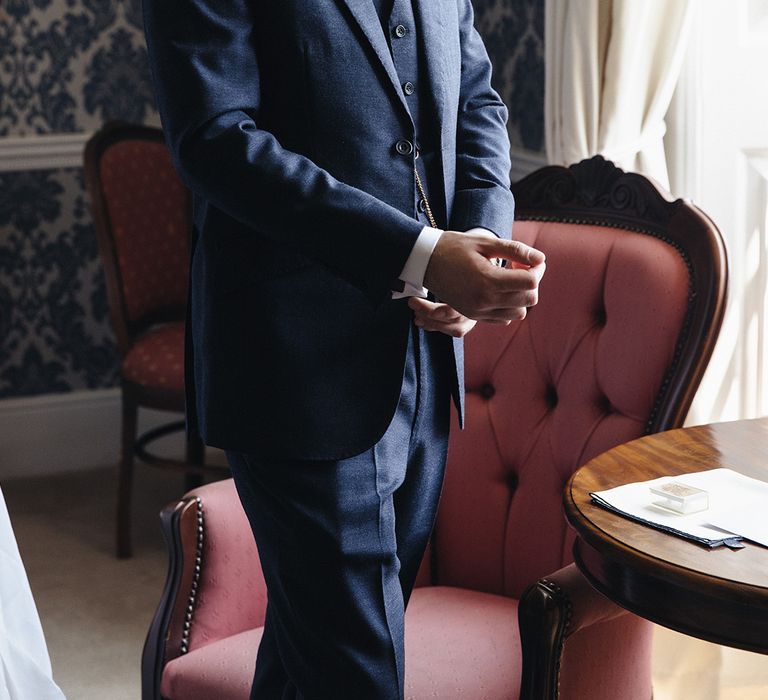 Groom in three piece navy wedding suit getting ready for the wedding 