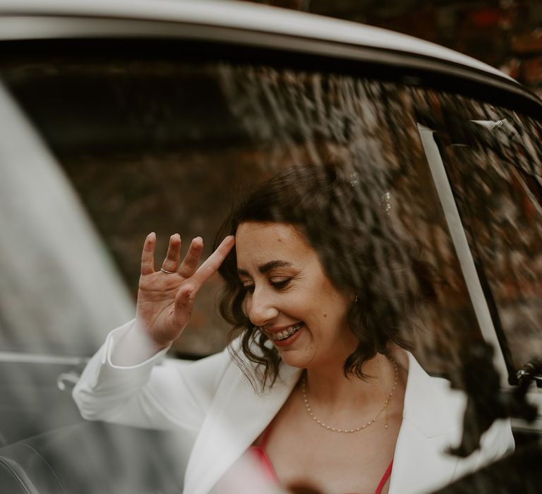 Bride in white wedding suit rides in retro wedding car on the way to the wedding ceremony 