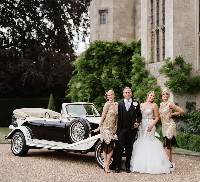 Bride and groom with gold sequin 1920s inspired flapper girls with black and cream vintage wedding car 