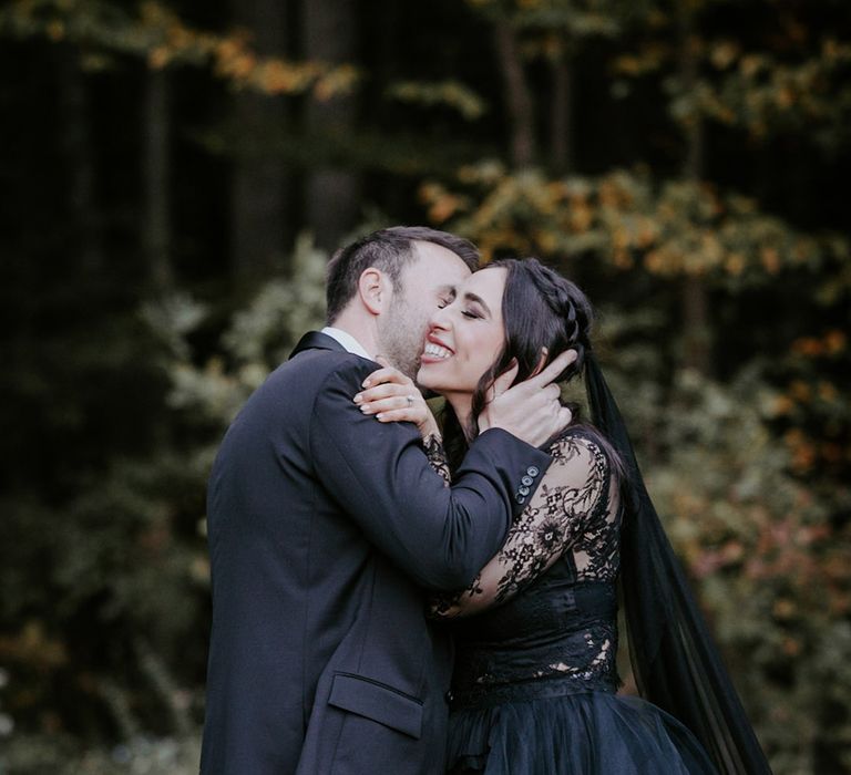 Romantic couple portrait with the groom kissing the bride on the cheek 