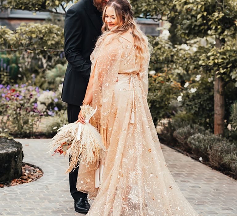 Bride in sheer gold metallic wedding dress with the groom in an all black wedding suit for their couple portraits 