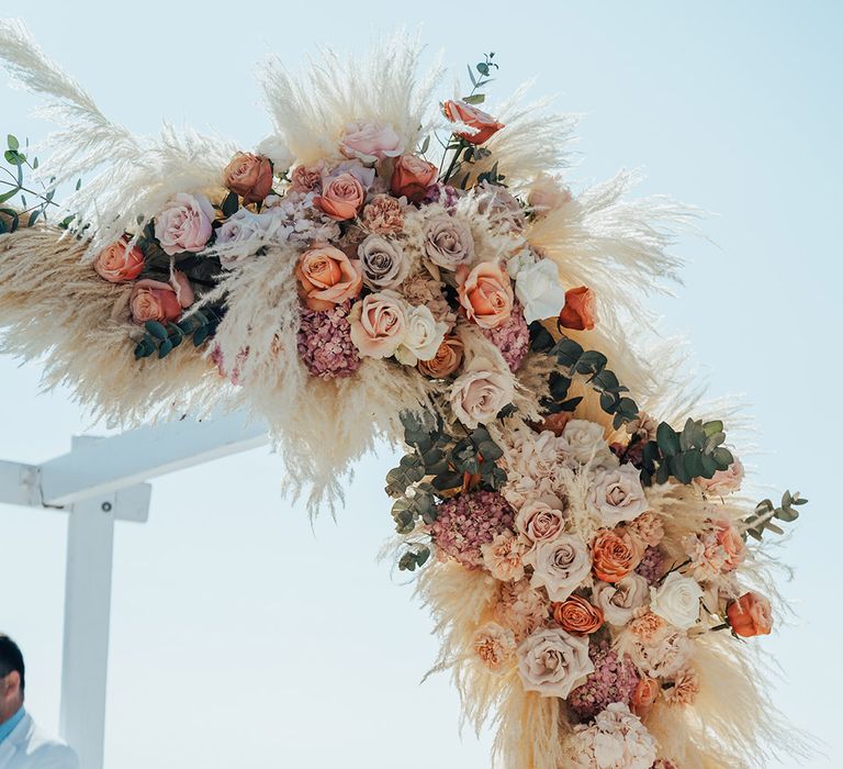 Pampas grass and rose flower arrangement attached to the wedding altar canopy 