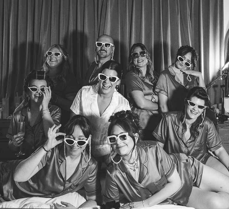 The bridal party poses fro group photo as they get ready for the wedding together in matching heart shaped sunglasses