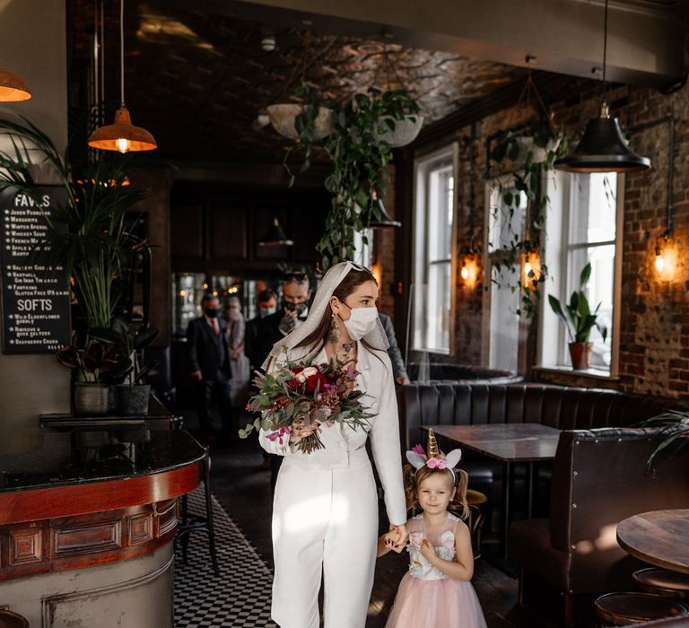 Bride in jumpsuit with flower girl in a pink tutu