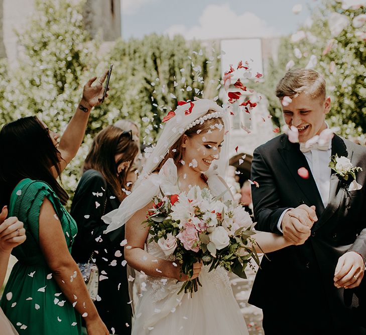 Bride and groom holding hands during confetti moment 