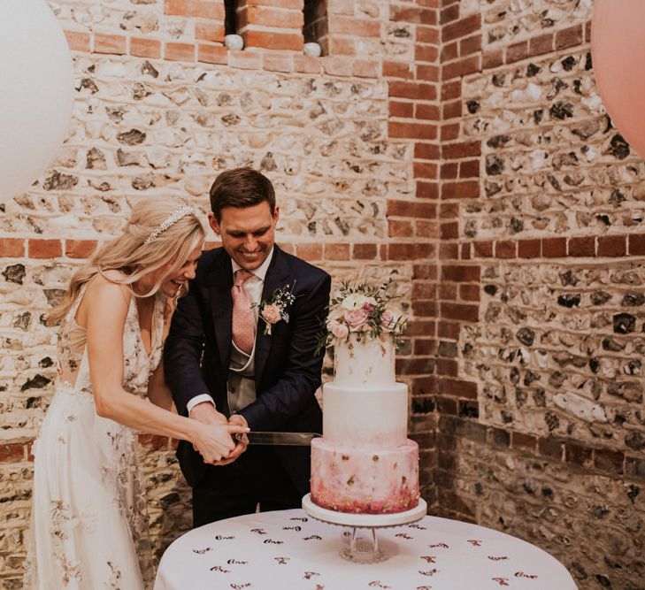 Bride and groom cutting their pink ombre wedding cake 