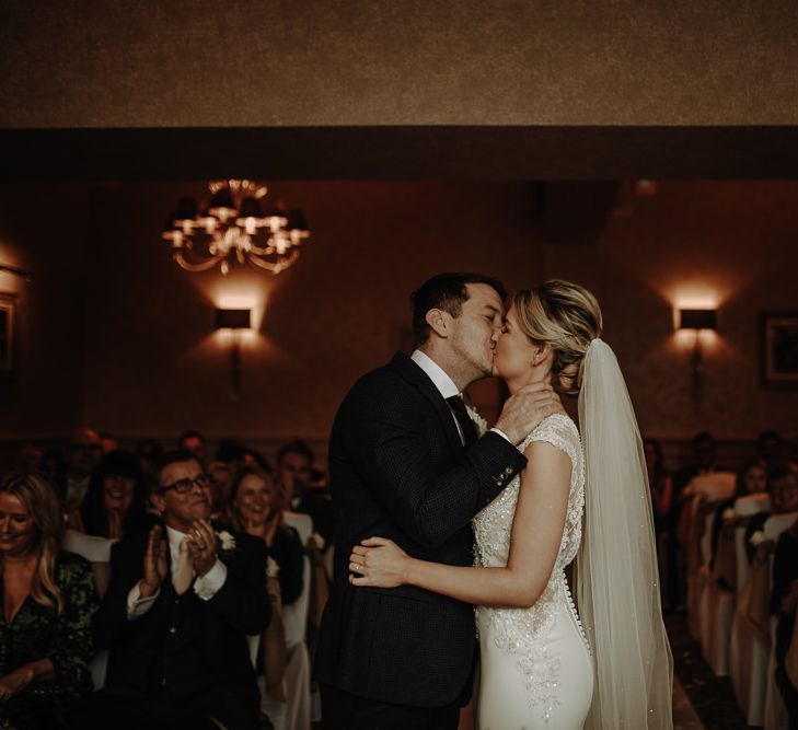 Bride and Groom kissing at Lake District wedding ceremony with warm atmospheric lighting