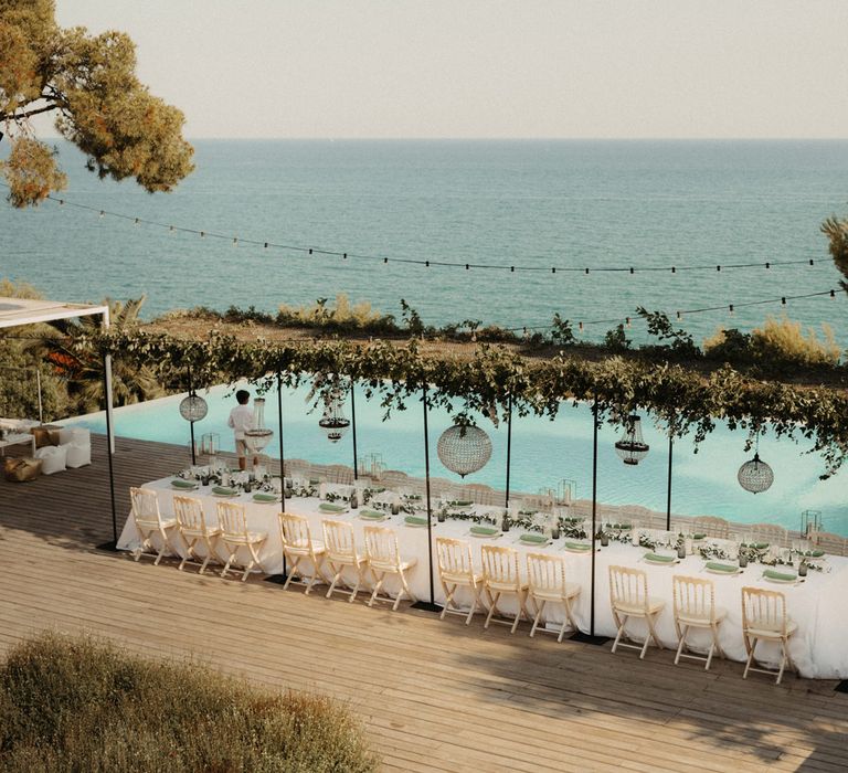 Intimate outdoor wedding reception by an infinity pool 