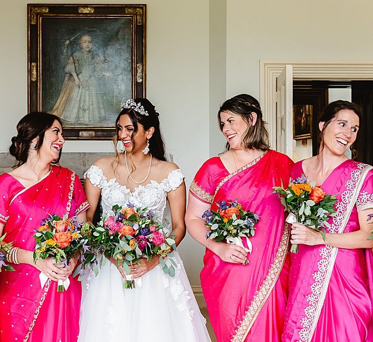 Bride in a lace wedding dress and bridesmaids in hot pink dresses on the wedding morning 