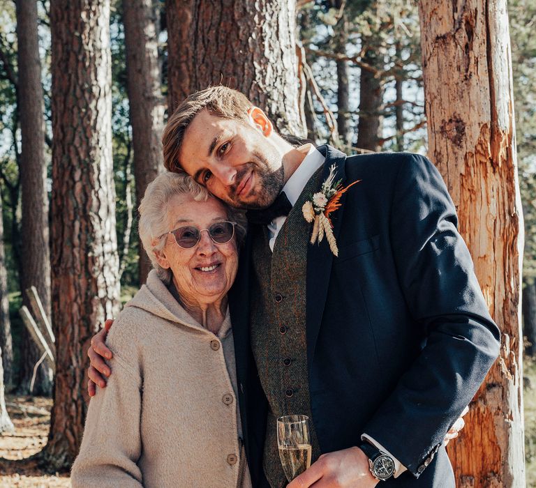 Groom hugs wedding guest in woodland wedding