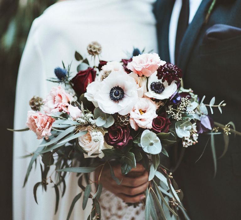 Bride holding white anemone and pink and red rose wedding bouquet