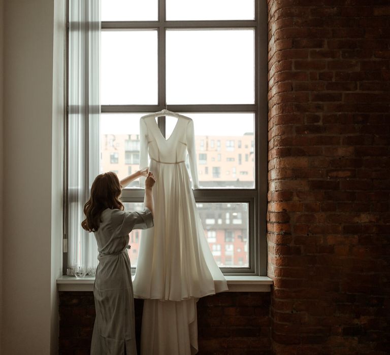 Bride hanging up her bespoke Rita Colson wedding dress