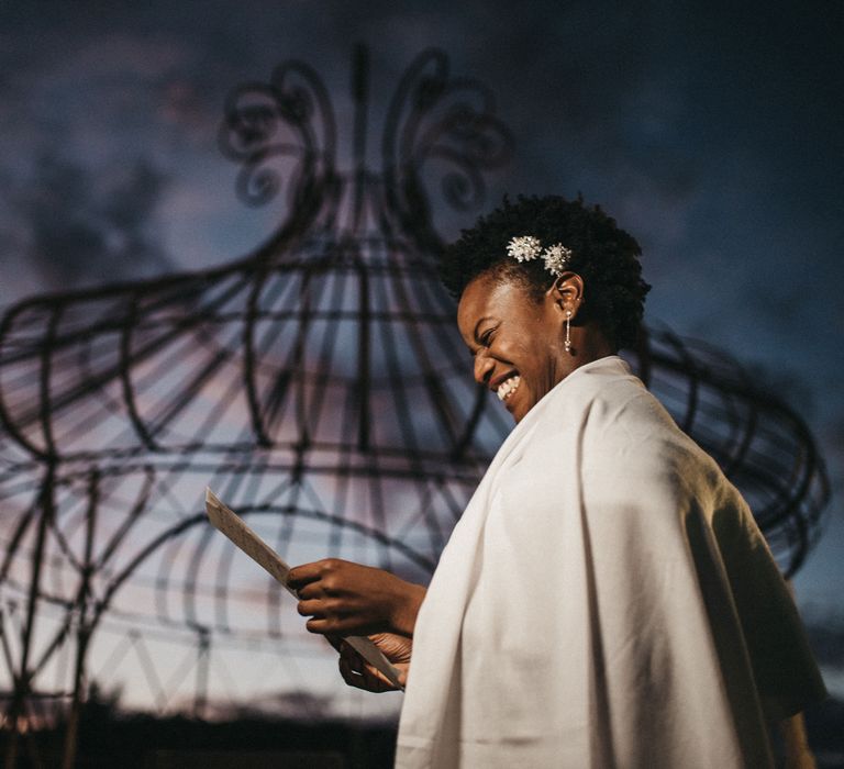 Smiley West African bride reading her vows at an outdoor wedding ceremony near Paris, France. 