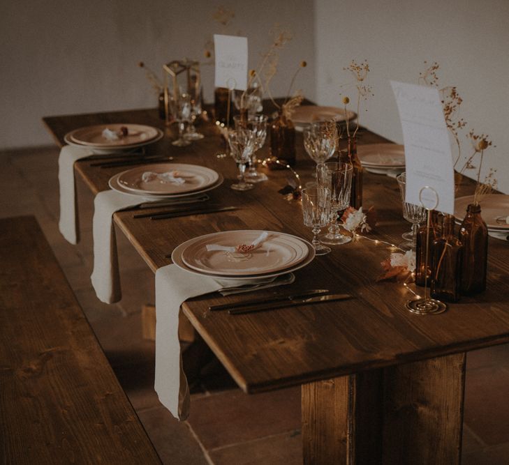 minimalist table decor with coloured plates, and dried grasses in vases as centrepiece decor 