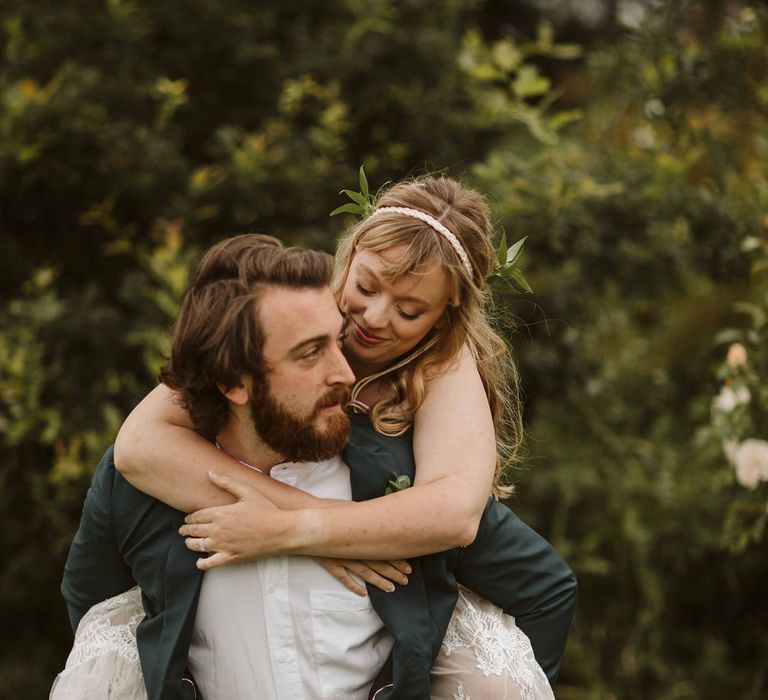 Bride is carried on grooms back outdoors