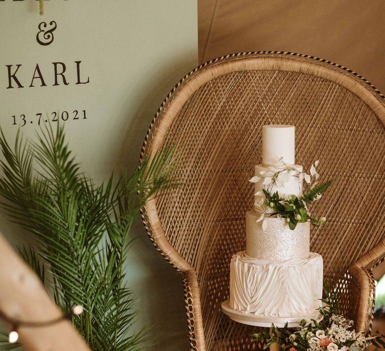 Wedding cake featuring green floral design and decor with wooden chair