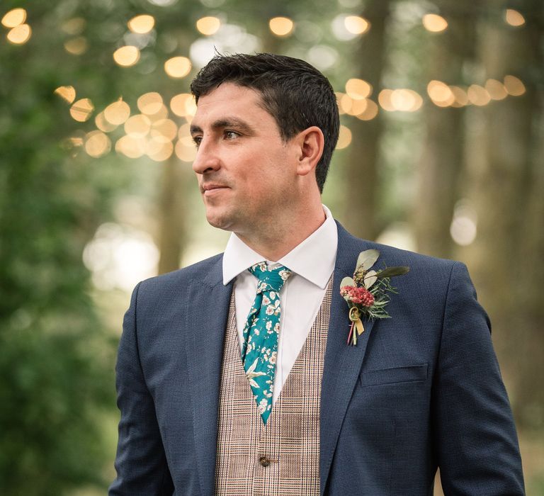 Groom wears blue suit with waistcoat and floral buttonhole