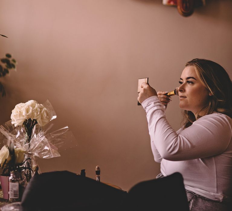 Bride applies her own blusher on the morning of her wedding