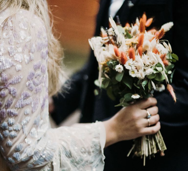 Bride holding white and peach bridal bouquet with lace sleeved bridal gown