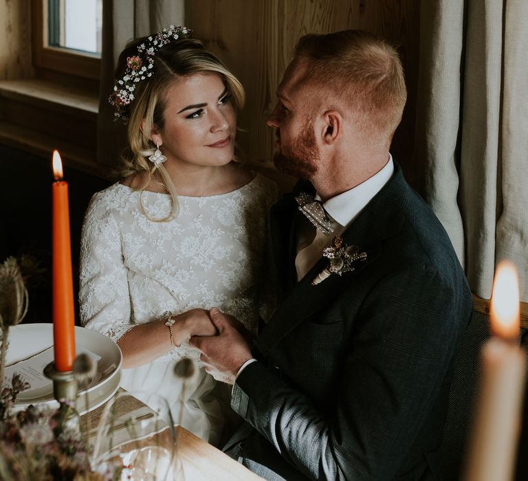 Bride and groom sitting at their Dolomites wedding reception with the bride wearing petal earrings 