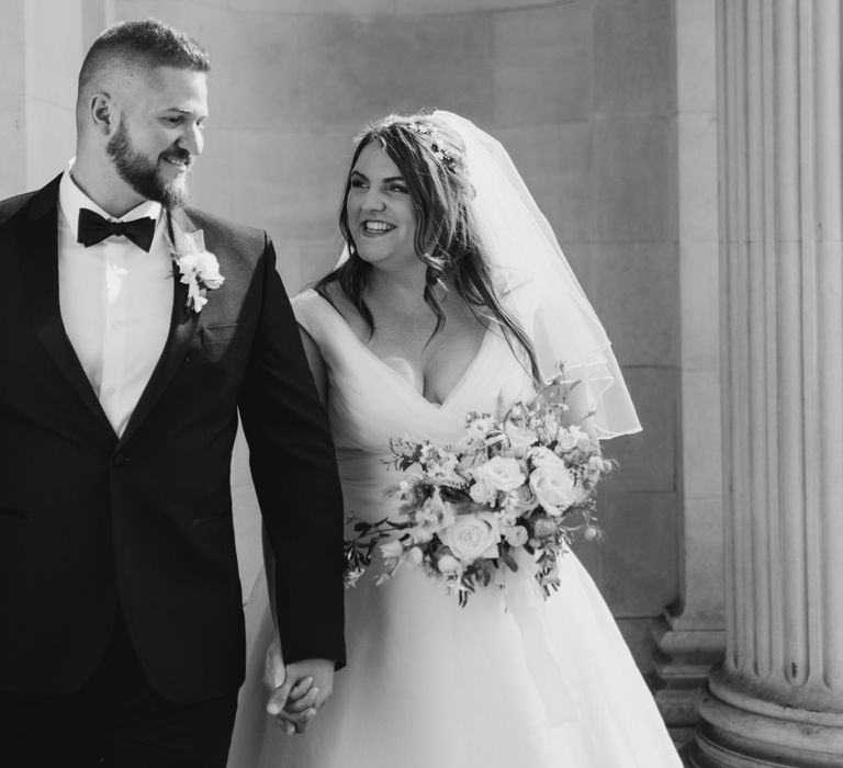 Bride looks up lovingly at groom as he wears black tuxedo on their wedding day