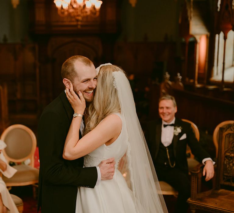 Bride kisses and hugs her groom as they meet for the first time before wedding ceremony whilst wedding guests look on