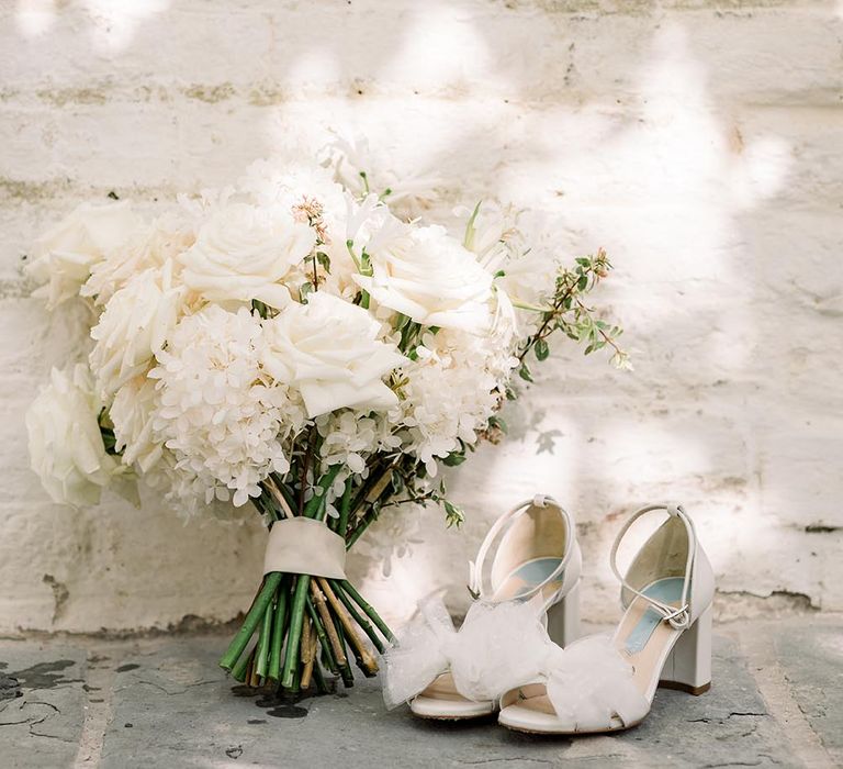 all white rose and hydrangea wedding bouquet and Charlotte Mills bow wedding shoes 