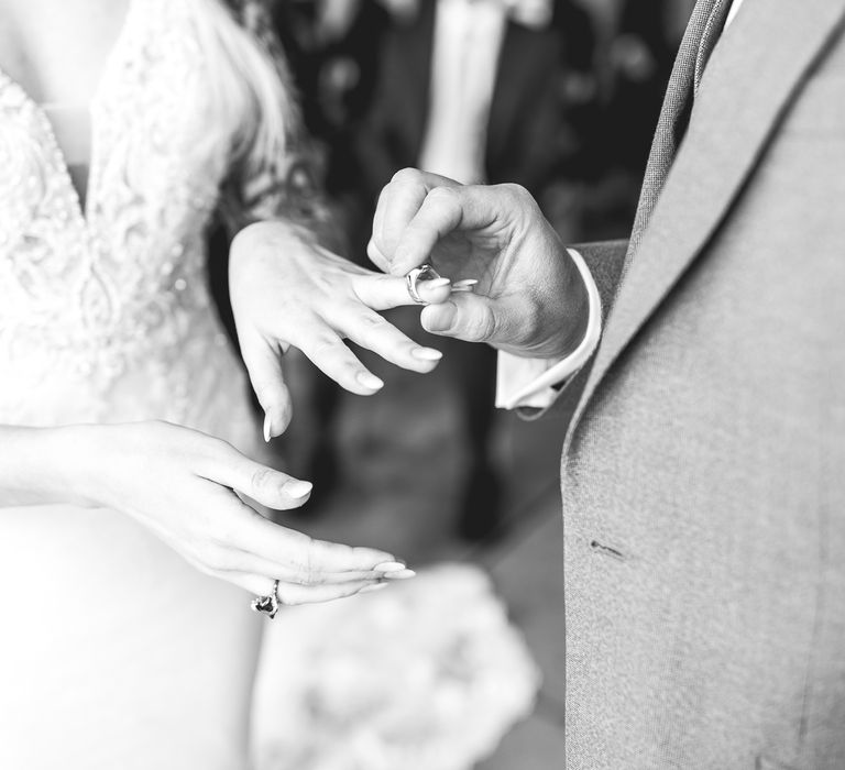 Black & white image of groom giving bride ring on wedding day