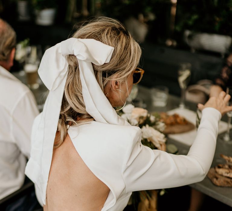 Stylish bride in a short wedding dress with open back wearing an Aura Bridalwear bow in her hair 