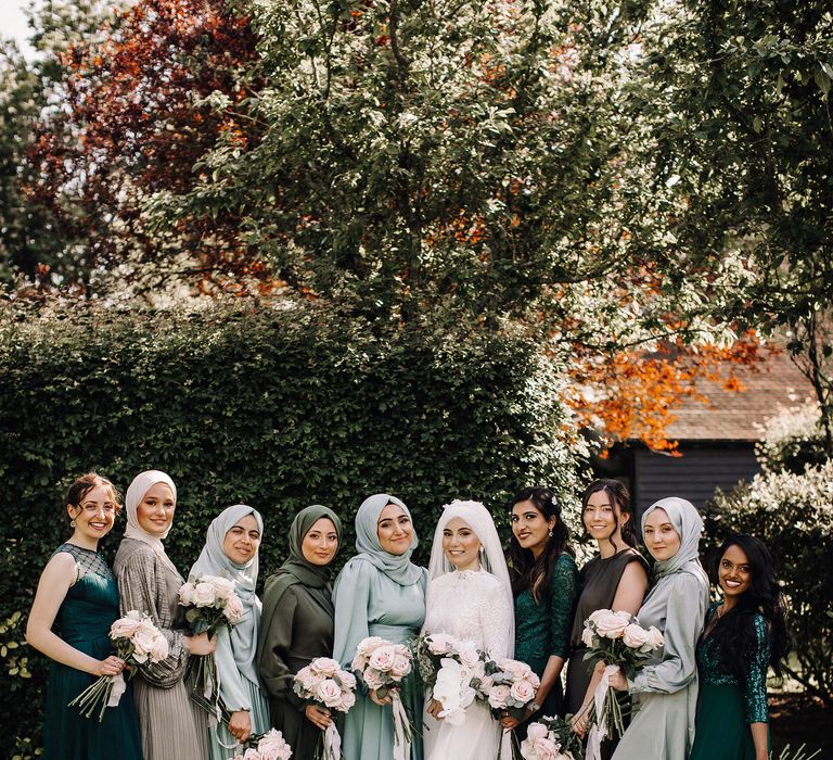 Bride with bridesmaids in various shades of green and styles of dress with traditional islamic items