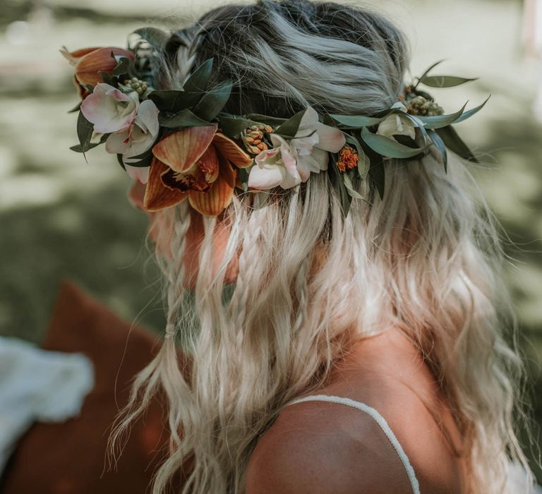 Bride with blonde beach waves and tropical flower crown sits outside for birds of paradise wedding inspiration