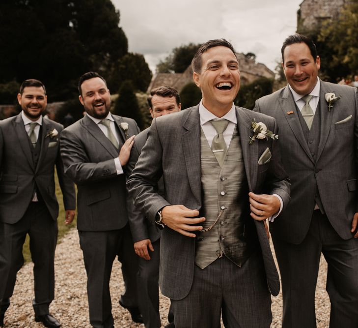 Groom and groomsmen in grey wedding suits with the groom in a different fabric waistcoat to stand out 