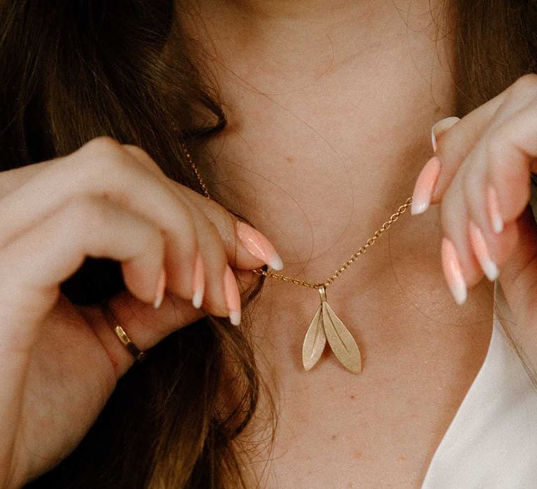 Bride with french manicured nails holding her custom necklace from recycled gold by Elizabeth Terzza Jewellery