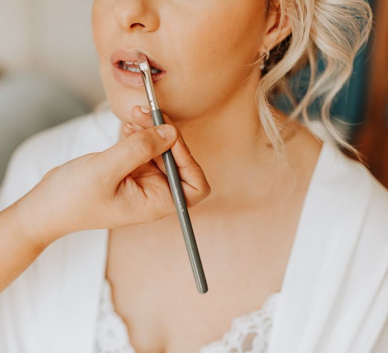 Bride gets a neutral lipstick applied during preparations